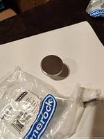Single Amerock nickel cabinet/drawer pull with original packaging and mounting screw visible on a white background.