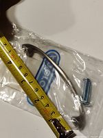 Single Amerock nickel cabinet/drawer pull in original packaging next to measuring tape showing pull length approximately 3.75 inches.