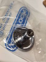 Close-up of one round polished nickel knob from Amerock in original plastic packaging.