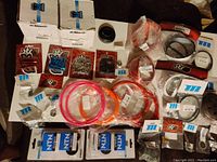 Array of scooter and moped parts in original packaging including bolts, screws, rubber gaskets, and boxed bearings.