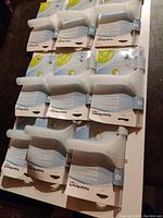 Photo of nine new, unused Total-Reach shower squeegees, white handles, each packaged in original blue and white cardboard holders.