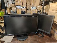 Two monitors together showing front screens and stands, Asus monitor prominent in front.