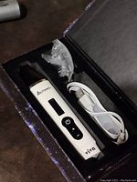 Front view inside box showing AUTLOOPS vaporizer, USB charging cable, and clear small parts.