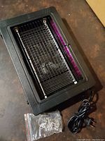 Top and side angle view of rectangular black mosquito trap with purple UV LED tube and metal grid zapper, showing power cord and mounting accessories.