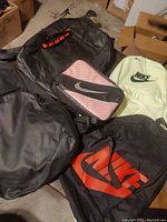 Overview of 5 Nike bags showing condition and style variety including black, pink, and yellow bags