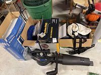 Photo showing Poulan Pro gas blower vac in open box with attachments and Toro blower vac black unit also visible along with Lasko fan box and some accessories.