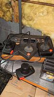 Atari 2600 console with three joystick controllers and cables, including some game cartridges partially visible