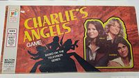 Top view of Charlie's Angels game box showing the title and images of Kelly, Jill, and Sabrina with the age recommendation and Milton Bradley logo.