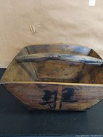 Top angled view of wooden box showing inside, wooden handle, and Chinese characters on the outer panel.