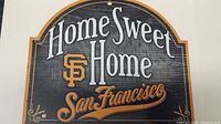 Front of wooden sign with 'Home Sweet Home' text, Giants logo, and 'San Francisco' in script.