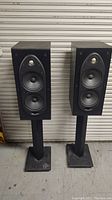 Pair of Polk Audio RT55 bookshelf speakers on black stands, front view showing the drivers and tweeters.