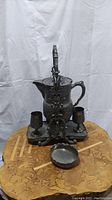 Full view shot showing entire antique 1800s ice water pitcher set on decorative wooden table including pitcher, tray, and two glasses.