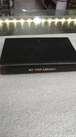 Closed black hardcover journal with gold embossed spine title 'MY TRIP ABROAD'