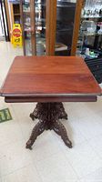 Full view of the square mahogany table top and carved pedestal base.