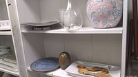 Shelves with various decor and kitchenware items including vase, pottery, spoons, and plates.