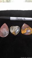 Three gemstone pendants arranged side by side with a Sharpie marker above for size comparison.