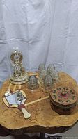 Photo showing lot contents on wooden table: glass dome clock, seven glass insulators, stained glass mirror, and round wicker basket
