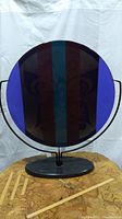 Front view of the round blue and purple glass sculpture with butterfly motif mounted on black marble base.