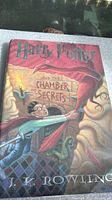 Front cover of the Harry Potter and the Chamber of Secrets book showing illustrated artwork of Harry flying on a broomstick and snake.