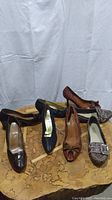 Overview of five pairs of vintage women's leather shoes arranged on a wooden surface, showing various styles and colors