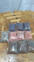 Ten sealed plastic bags containing various colors of vintage small round glass beads displayed on a patterned surface.