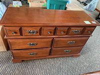 Front view showing the full dresser with six drawers, medium brown wood, metal handles, and decorative trim.