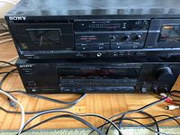 Sony dual cassette deck stereo and Sony stereo receiver stacked, showing buttons, dials, and input/output connectors