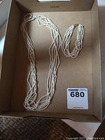 6-strand seed pearl matching necklace and bracelet displayed in box.