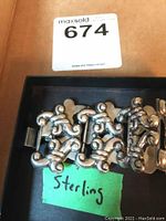 Sterling silver bracelet with 7 ornate links visible from above with a label saying 'Sterling'.