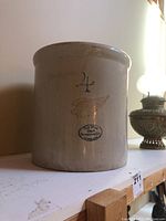 Front side of the large stoneware crock, showing overall shape and size relative to surroundings.