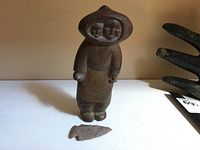 Front view of full carving showing mother figure in parka with child’s face inside hood.