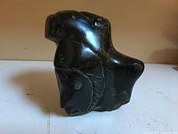 Dark polished soapstone carving of a bear with visible carved details and natural white veining.