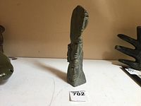 Front side view of the Inuit soapstone totem pole carving showing three carved faces stacked vertically.