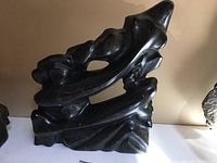 Front view of dark soapstone carving showing two fish and wave forms