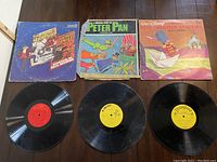 Three children's vinyl LP records laid out with their illustrated sleeves: 3 Musketeers/Oliver Twist, Peter Pan, and Walt Disney Hans Christian Andersen.