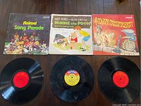 Three children's vinyl LP records and their sleeves: Animal Song Parade, Walt Disney Winnie the Pooh and the Honey Tree, and Happy Instruments, arranged side by side.