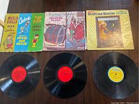 Three children's vinyl LP records lined up, showing their covers and records below them, labels partially visible.