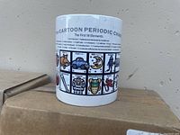Photo showing front side of a mug featuring cartoon style representations of the first 18 elements of the periodic table including Boron, Carbon, Nitrogen, Oxygen, Silicon, Phosphorus, and Sulfur.