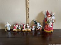 Set of six Christmas-themed ornaments and figurines arranged in a row for size reference with a ruler showing height.