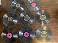 Photo showing eight vintage 78 RPM records laid out on wooden surface, various labels visible including Victor and Okeh.