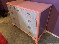 Front angled view of hardwood dresser painted light blue with peach trim, showing four large lower drawers and three smaller upper drawers with original brass hardware.