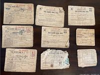 Photo showing nine worn World War II war ration books from 1943-1945, some with stamps and handwritten owner info.