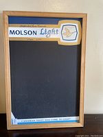 Front view of Molson Light chalkboard sign with wooden frame. Features branding and black chalkboard surface.
