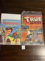 Two items side by side: The Adventures of Robin Hood hardcover book and True Comics #26 comic book in plastic sleeve.