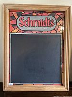 Full view of Schmidt's chalkboard mirror sign with wood frame showing stained glass style background and chalkboard area.