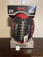 Front view of the official Spalding XFL football in original box showing the football and box branding.
