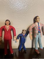 Photo showing three figures: woman in red suit, conductor in blue uniform, and man in plaid jacket.