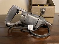 Side view of vintage Craftsman electric drill with attached power cord, resting on table.