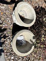 Two stone planters shown from above, inside empty, placed on mulch ground.
