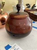 Koa wood jar with lid, carved leaf design, polished finish.